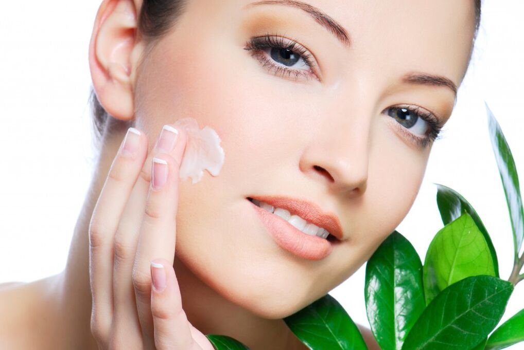 a girl paints her face with a rejuvenating cream